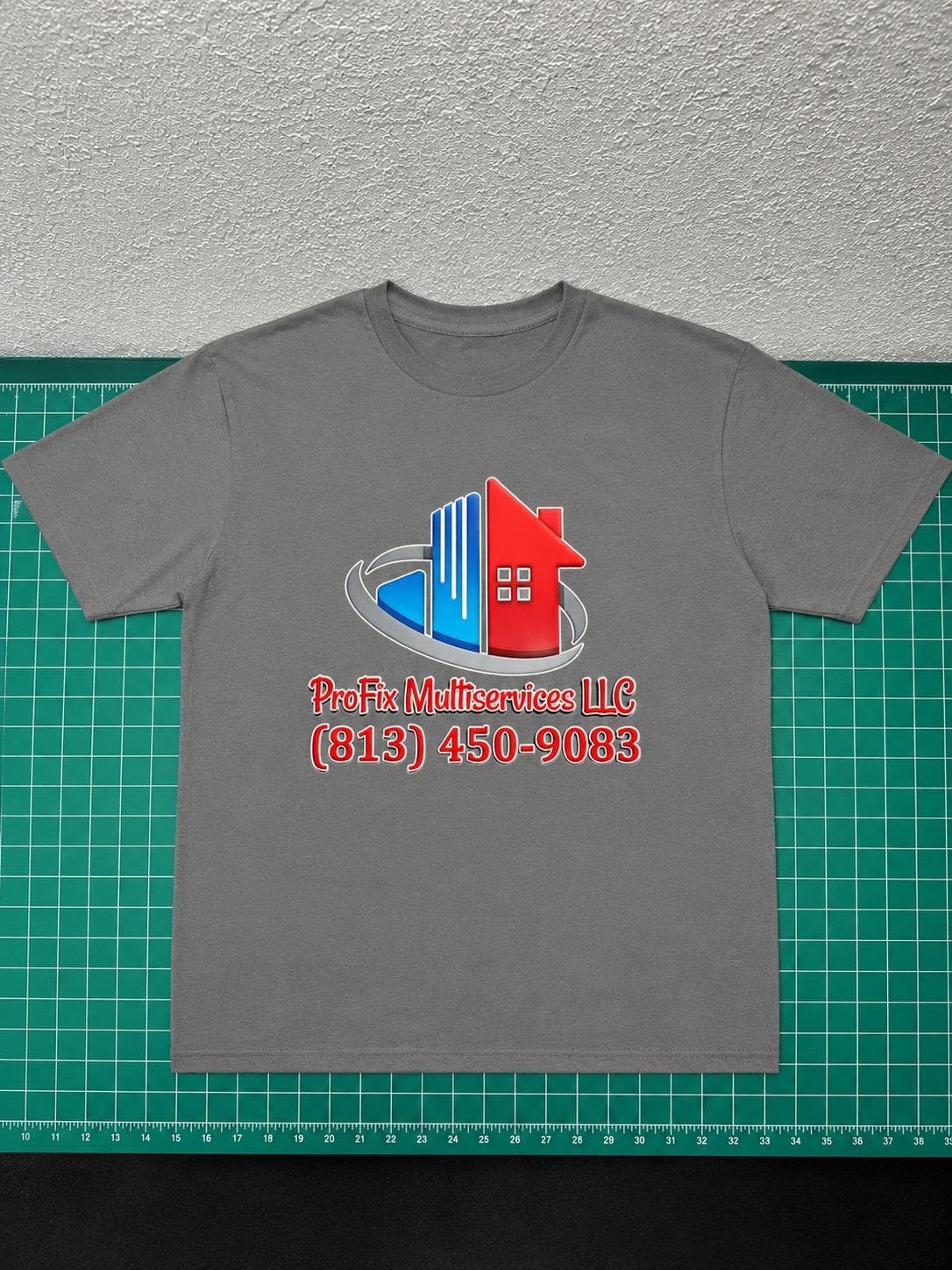 Camisa gris de ProFix Multiservices fotografiada sobre tapete de corte verde