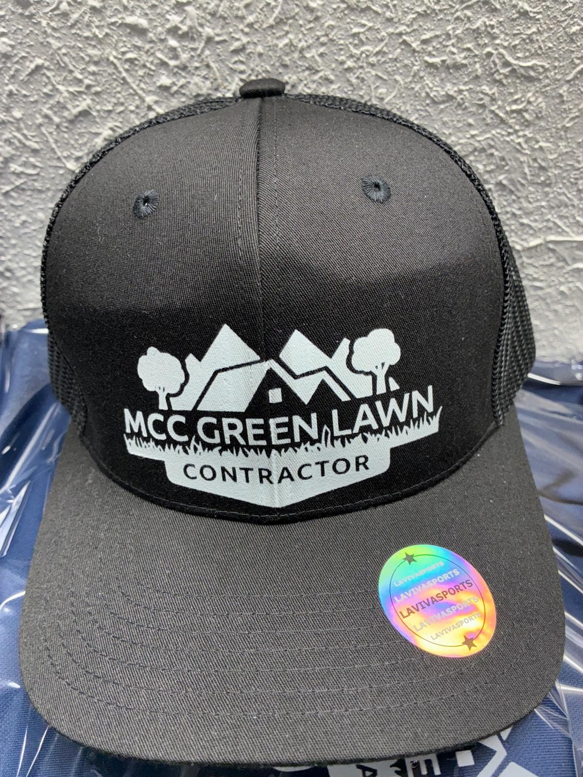 Gorra trucker negra con logo blanco de MCC Green Lawn Contractor