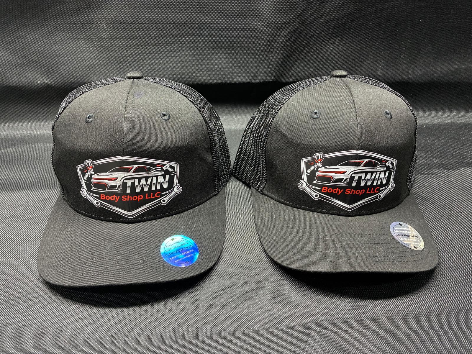 Dos gorras trucker negras de Twin Body Shop en fondo de estudio