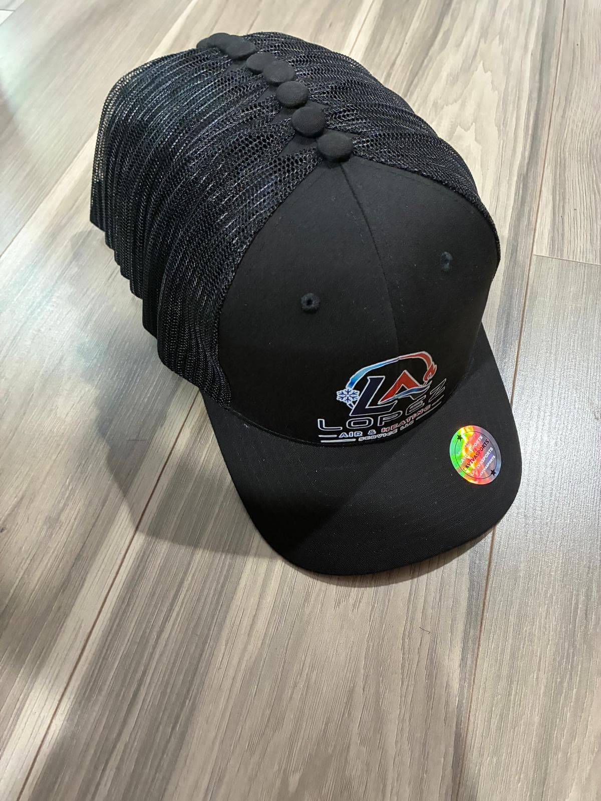 Pila de gorras trucker negras de Lopez Air & Heating