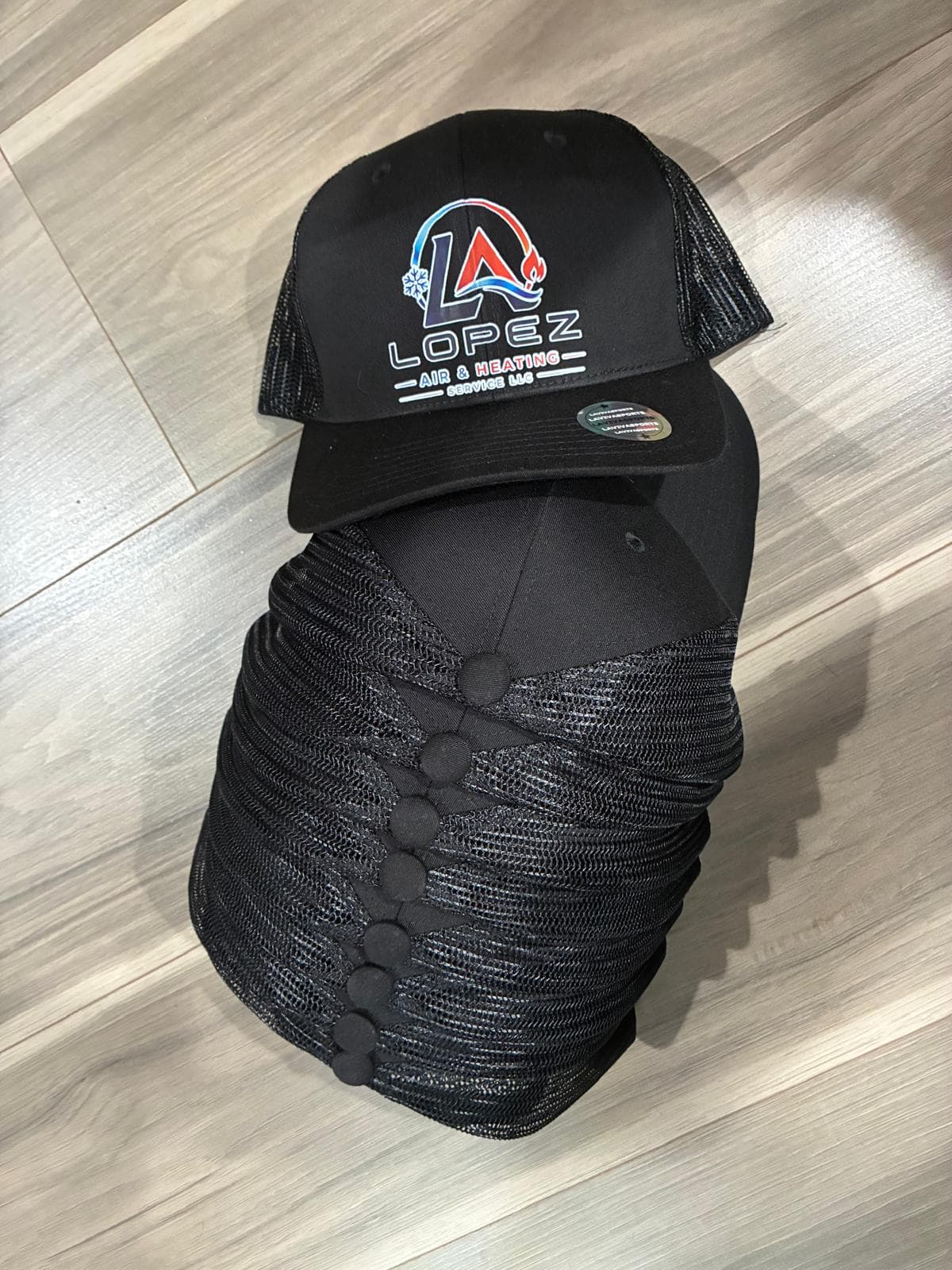 Pila de gorras trucker negras de Lopez Air & Heating Service